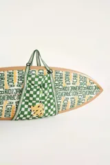 Bolso tipo sling de tamaño mediano con estampado a cuadros verdes y blancos y dibujo de bananas. Tiene tiras regulables que se extienden como asas y bolsillo frontal con elástico.