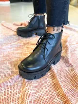 Botines negros de cuero con cordones y cierre lateral. Plataforma track con suela dentada.
