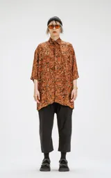 Camisa de manga corta color marrón con estampado geométrico en negro y blanco, calce oversize y canesú en la espalda.