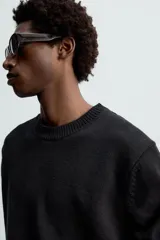Jersey negro de corte boxy fit, tejido en hilatura con mezcla de algodón y 13% de cashmere. Tiene cuello redondo, manga larga y acabados en rib.