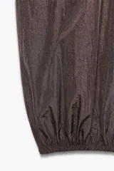 Pantalón bombacho marrón de nylon con cintura elástica, bolsillos laterales ocultos y bajo abullonado con elástico.