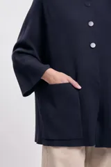 Capa azul marino de tejido de punto con cuello mao, cierre frontal con botones y bolsillos de parche.