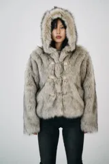 Chaqueta corta de pelo sintético color gris con capucha y cierre frontal con broches metálicos.