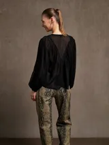 Blusa color crema con cuello redondo, botones frontales y mangas largas abullonadas.