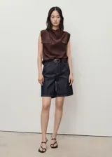 Short de jean azul oscuro, tiro alto, con cinco bolsillos, cierre frontal con cremallera y botón, trabillas para cinturón y corte recto.