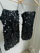 Vestido corto negro con lentejuelas de distintos tamaños, tirantes finos elastizados y cierre en la espalda.