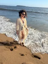 Túnica larga de gasa color beige claro, con mangas largas y cuello en V, con detalle de amarre frontal.