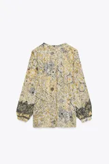 Blusa estampada con hilo metalizado, cuello redondo con volante, escote pico y manga larga abullonada.