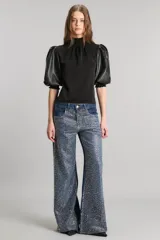 Pantalón de jean de tiro medio y corte wide leg, color azul denim, con apliques de strass plateados simulando una lluvia de brillantes. Confeccionado en tejido denim 100% algodón.