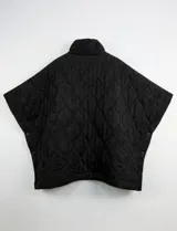 Poncho acolchado color mostaza con cuello alto y abertura frontal con cierre. Presenta un patrón capitoné de formas ovaladas y bolsillos delanteros.