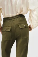 Pantalón tipo babucha color verde militar, confeccionado en gabardina elastizada, con ajuste en tobillos y cintura regulable con cordón a tono. Cuenta con bolsillos diagonales en el frente y bolsillos con solapa y botón en la parte trasera.