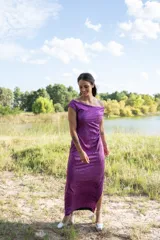 Vestido midi color violeta con textura brillante, escote off-shoulder y mangas cortas.