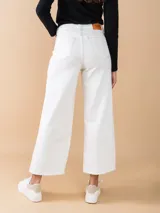 Jean ancho color crudo con corte recto, tiro alto y ruedo deshilachado.