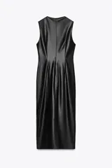 Vestido midi negro de cuero sintético, sin mangas, con cuello redondo, frunces y pieza metálica dorada en el delantero, abertura en el bajo y cierre trasero con cremallera oculta.