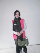 Cartera negra de lona semi impermeable con cierre metálico, forrería de gross y bolsillo interno. Tiene tira regulable y etiqueta blanca con texto en el frente.
