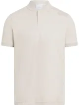 Chomba color beige claro de algodón suave, con cuello mao, manga corta y cartera con dos botones. Tiene un parche con micro logo en la parte delantera.