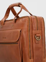 Maletín de cuero color caramelo con doble asa de mano y correa bandolera ajustable y extraíble. Tiene un bolsillo frontal con cierre y compartimentos internos para organizar documentos y dispositivos electrónicos.