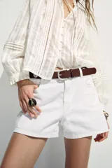 Shorts de jean blancos, tiro medio, corte mom fit, con cinco bolsillos y cierre frontal con cremallera y botón.