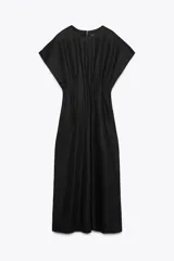 Vestido midi color marrón confeccionado en hilatura con mezcla de algodón y lino. Tiene cuello redondo, manga corta caída y detalle de pliegues en la cintura. Cierre en la espalda con abertura y botón.