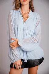 Camisa blanca de plumetí con cuello mao, mangas largas abullonadas con puños elásticos y cordón con borlas en el escote.