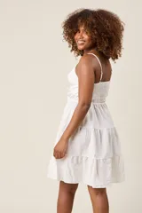 Vestido corto color verde claro, con tirantes finos, detalle de lazo en el escote y falda con volantes escalonados.