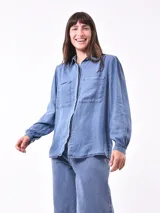 Camisa celeste de denim con dos bolsillos frontales con solapa y manga larga con puños abotonados.