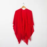 Ruana roja de tejido de punto calado con flecos en el borde inferior.