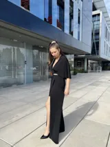 Vestido negro largo con escote en V, mangas cortas tipo kimono, falda cruzada con abertura y cinturón fino con strass.
