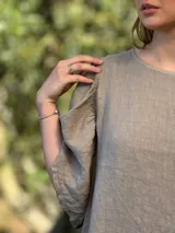 Vestido largo color beige, de corte amplio, con mangas cortas abullonadas y volado en el ruedo.