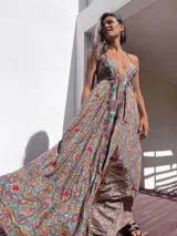 Vestido largo con estampado paisley en tonos marrones, celestes, dorados y fucsias. Tiene escote halter con tirantes finos y bordados rojos en el frente.