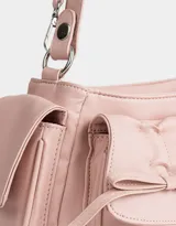Bandolera rosa claro de cuerina con manija superior y cierre principal. Presenta doble bolsillo frontal y bolsillos laterales, todos con broche lazo con botón para cerrado.