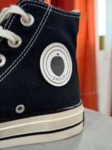 Zapatillas de lona blancas de caña alta con cordones y puntera de goma. Logo de durazno engomado en la base y en la cara interna.