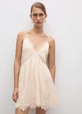 Vestido corto color crema con tirantes finos y escote en V, con detalles de encaje en escote y ruedo.