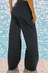 Pantalón ancho azul de tiro alto confeccionado en lino, con bolsillos delanteros con falsos botones y cierre lateral con cremallera oculta.