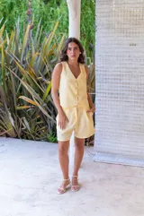 Conjunto de dos piezas color rojo vibrante, compuesto por un chaleco sin mangas con escote en V y botones frontales, y un short de tiro alto con pliegues y bolsillos laterales.