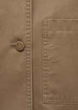 Chaqueta de algodón estilo tejano en color tostado, con diseño recto y manga larga con puños abotonados. Destaca por su cuello camisero de pana en contraste de color marrón oscuro, cierre frontal con botones y dos bolsillos de parche en el frente. Cuenta con forro interior.
