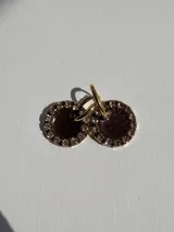 Par de aros colgantes con dije circular de resina con glitter multicolor y borde de strass. El arito es de acero quirúrgico dorado.