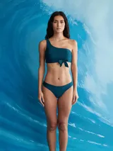 Conjunto de bikini color azul petróleo, con corpiño asimétrico de un solo hombro con nudo en el centro y bombacha colaless.