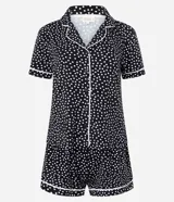Conjunto de pijama corto negro con lunares blancos y ribetes blancos. Incluye camisa de manga corta con cuello y botones, y short con cintura elástica.