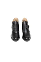 Botín de cuero negro con terminación charolada, hebilla plateada y taco medio de 5 cm.