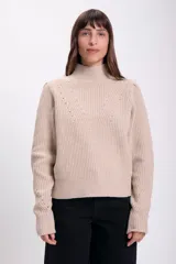 Sweater de punto color crudo, con cuello alto, manga larga y diseño holgado. Presenta un patrón de punto acanalado vertical y un diseño en forma de 'V' con pequeños agujeros decorativos en el pecho y los antebrazos.
