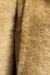 Abrigo largo color camel con efecto piel de oveja, cuello solapa, manga larga, bolsillos delanteros y cinturón ajustable con lazadas. Forro interior.