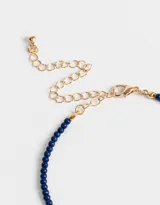 Collar corto de cuentas azul marino con dije de mosquetón dorado en forma de corazón y dijes colgantes de corazón dorado.