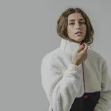 Buzo verde militar de sherpa con corte a la altura del pecho en tela lisa y cierre con cremallera amarilla.