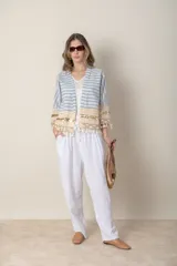 Chaqueta corta de jean rayada en tonos celeste y blanco, con apliques de puntilla y flecos en ruedo y mangas.