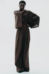 Pantalón blanco de lino, de corte ancho y tiro medio, con cintura elástica ajustable con cordones y bolsillos laterales.