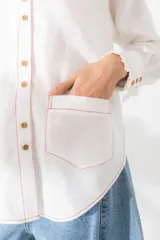 Camisa marrón de lino con cuello mao con volados, manga larga, cierre frontal con botones y bolsillo pequeño en el pecho.