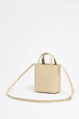 Bolso mini tipo tote de cuero color marrón claro, con doble asa corta, correa larga opcional y logo de la marca en el frente.