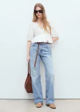 Blusa blanca con bordado floral, cuello de pico, mangas abullonadas tres cuartos y corte peplum.