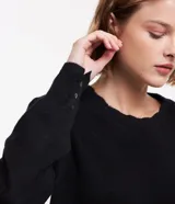 Suéter negro de punto con cuello redondo con acabado en forma de nube, manga larga con pliegues en los hombros y botones en los puños.